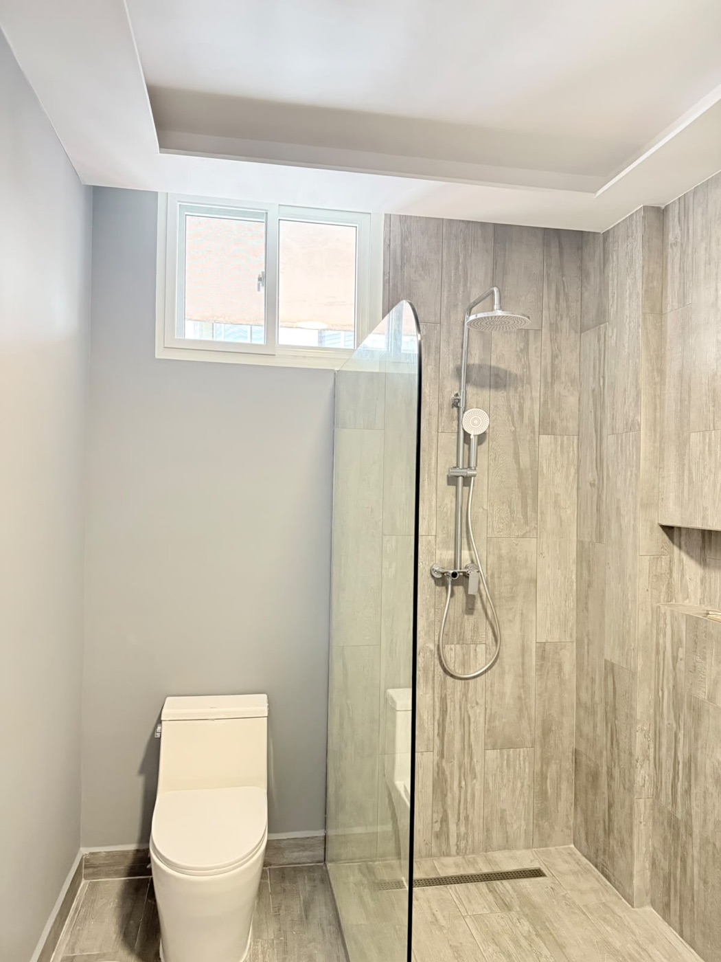 Baño con porcelanato símil madera y ducha en cristal templado en Condado del Rey